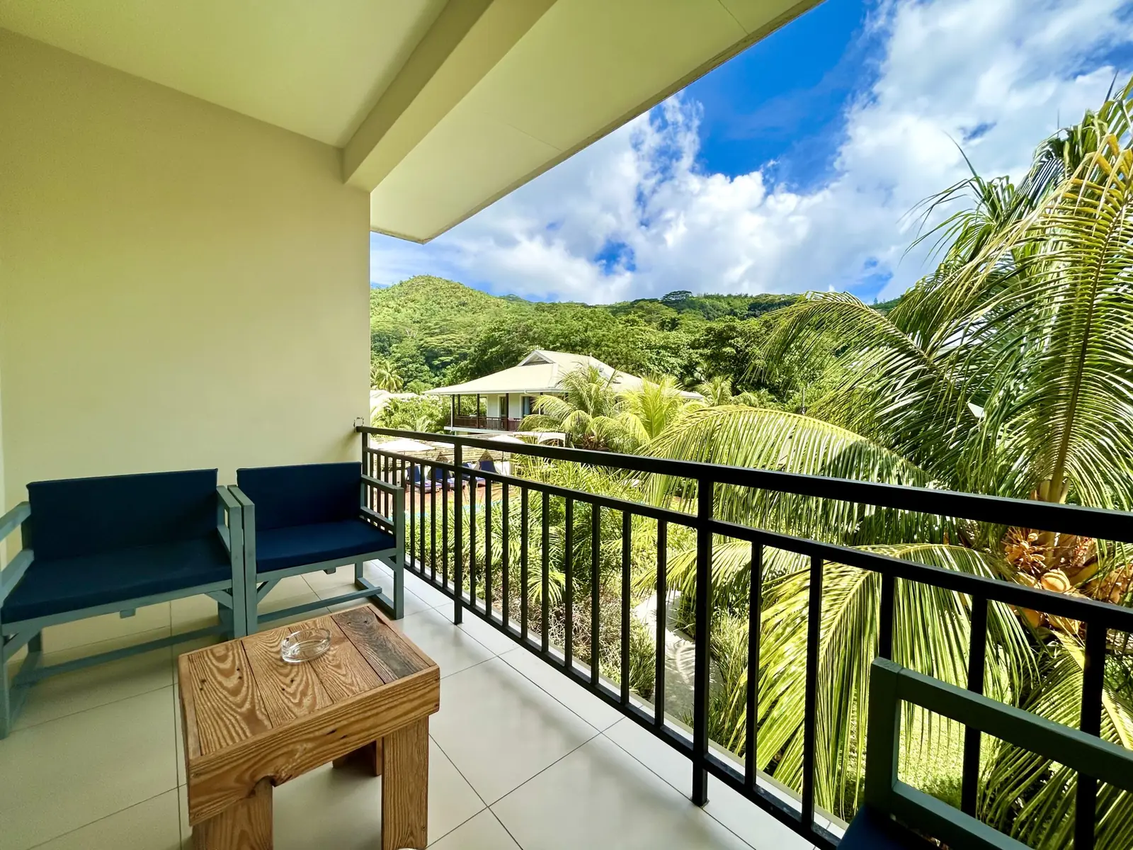 A shaded balcony looking out over palms to the hills