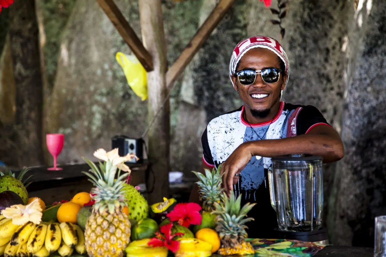 A smiling vendor with fresh fruit and a blender