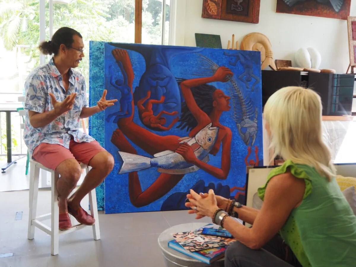 The artist talking with a guest beside one of his paintings